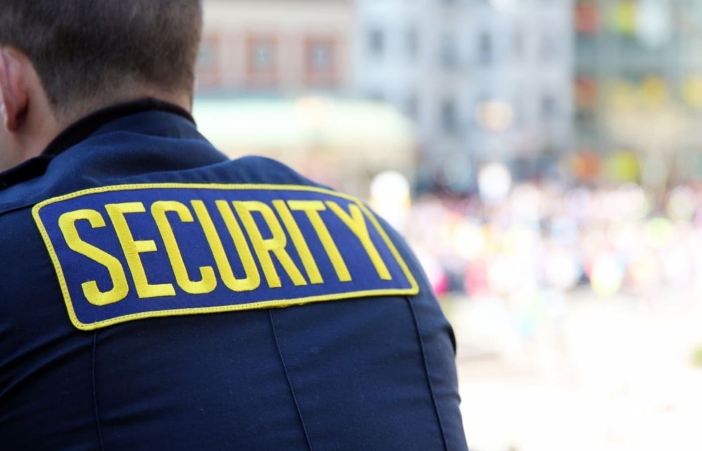 A security guard is seen from behind wearing his uniform.