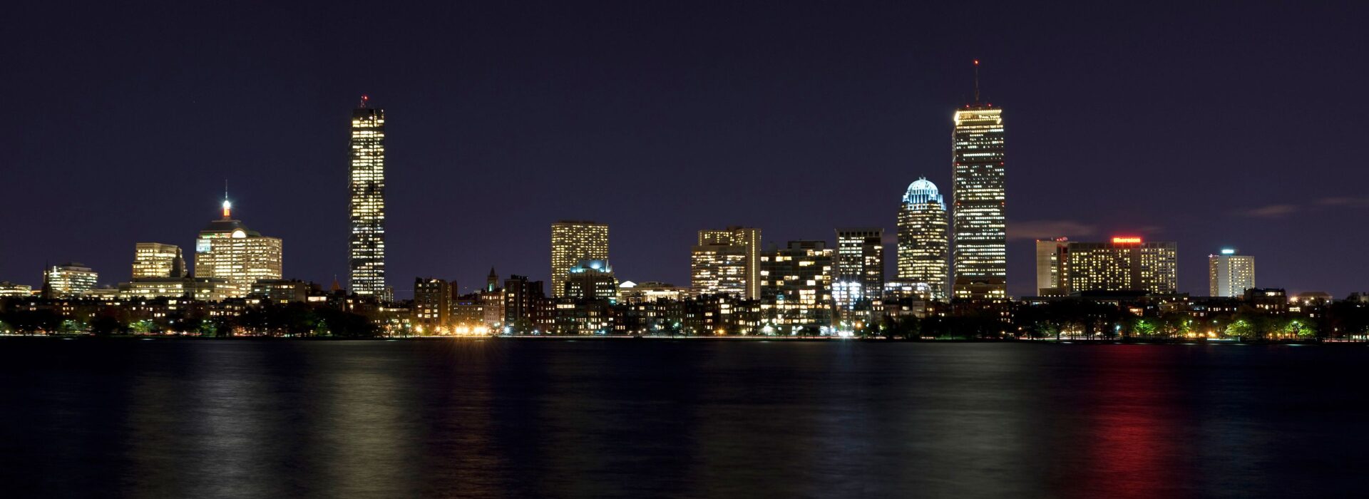 A city skyline at night with lights reflecting on the water.