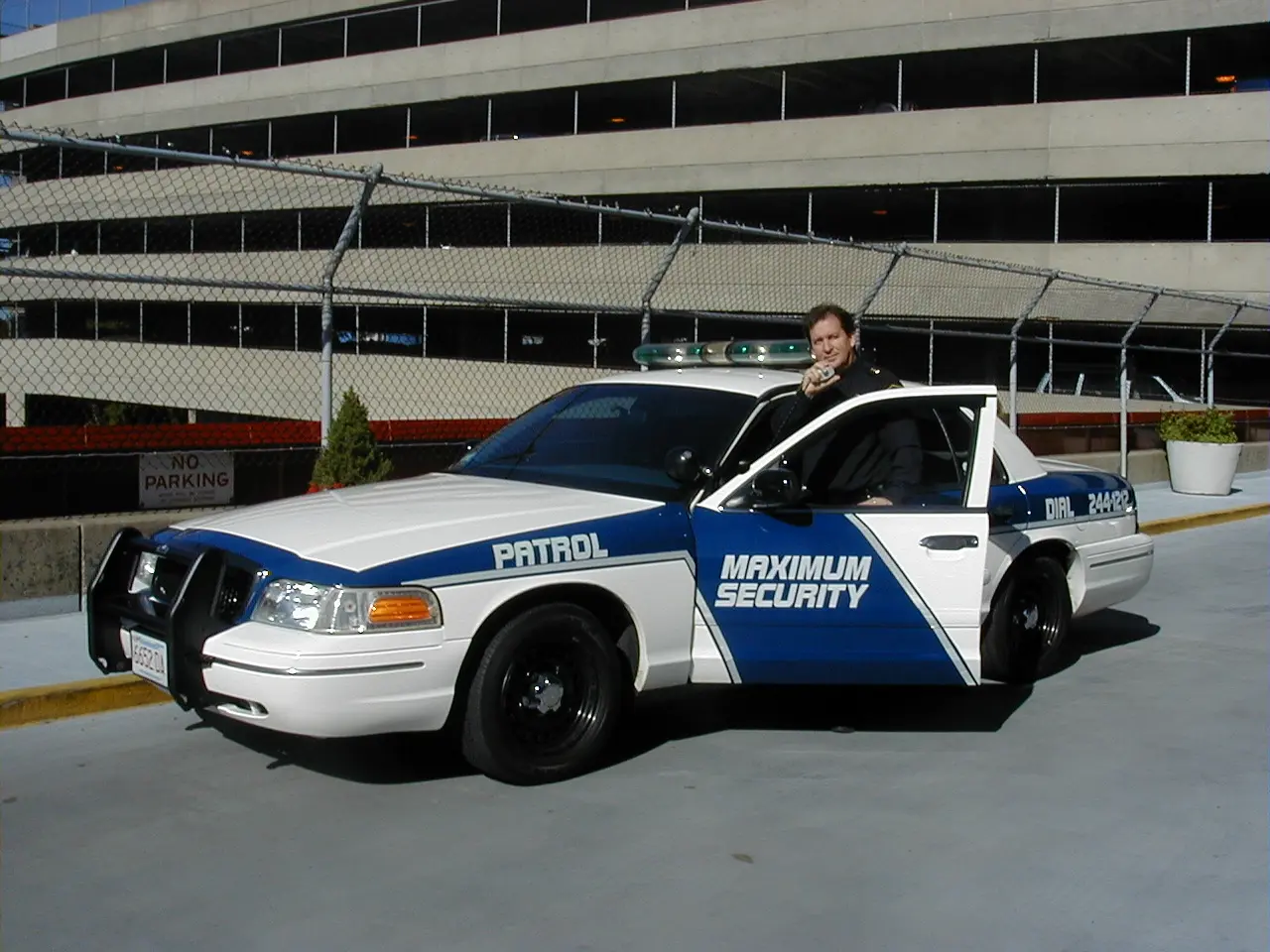 A man standing next to a police car.